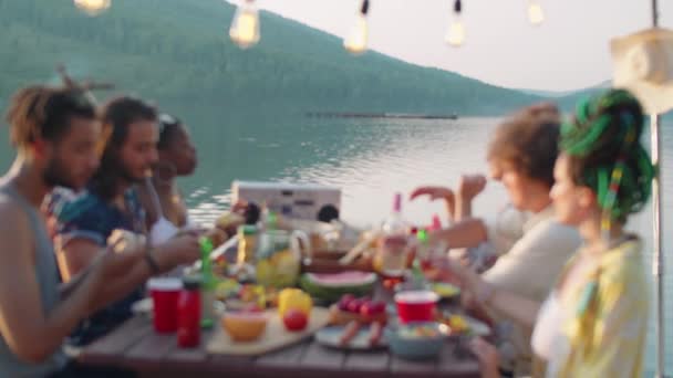 背景に風光明媚な湖と桟橋で屋外ディナーパーティーを持っている間に飲み物で試飲友人の会社の専用ショット — ストック動画
