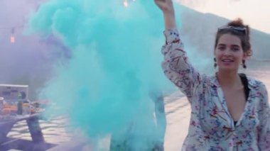 Genç ve çok ırklı güzel kadınlar göl partisinde renkli sis bombasıyla dans edip eğleniyorlar.