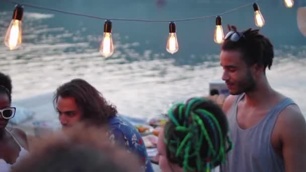ガーランドで飾られた桟橋で夜に湖のパーティーで飲み物で踊る若い幸せな多民族の人々の高角度ショット — ストック動画