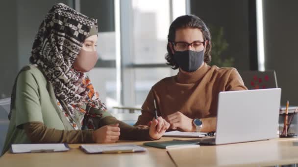 事務所に座っている保護マスクのイスラム教徒の実業家や中東のビジネスマンやコロナウイルスパンデミックの間に働く中でプロジェクトを議論 — ストック動画