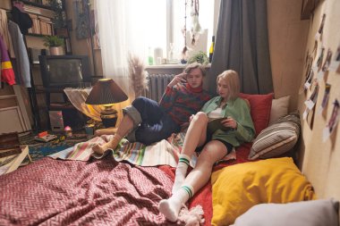 Genç çift odada kitap okuyor.