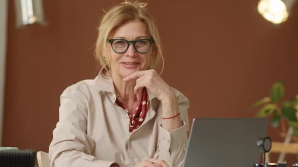 Zdjęcie Pozytywnej Starszej Bizneswoman Siedzącej Laptopem Biurze Patrzącej Kamerę Uśmiechniętej — Wideo stockowe