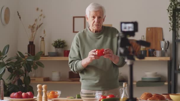 シニア男ショー新鮮な野菜と話上のカメラながら撮影フードVlogで台所に自宅 — ストック動画