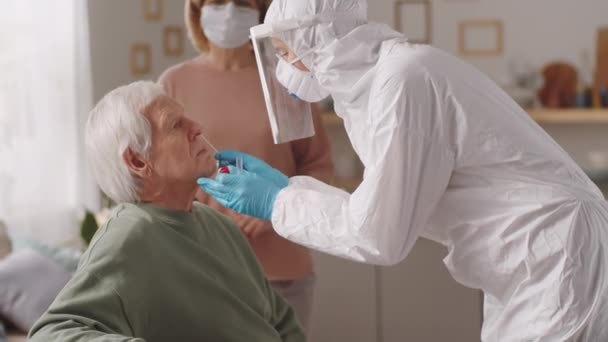 Lekarz Mundurze Ochronnym Pobierający Wymaz Nosa Starszego Mężczyzny Piszący Podkładce — Wideo stockowe