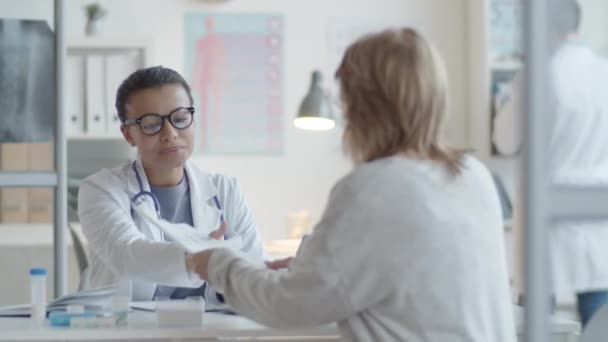 Junge Ärztin Sitzt Schreibtisch Begrüßt Frau Mit Handschlag Liest Ihre — Stockvideo