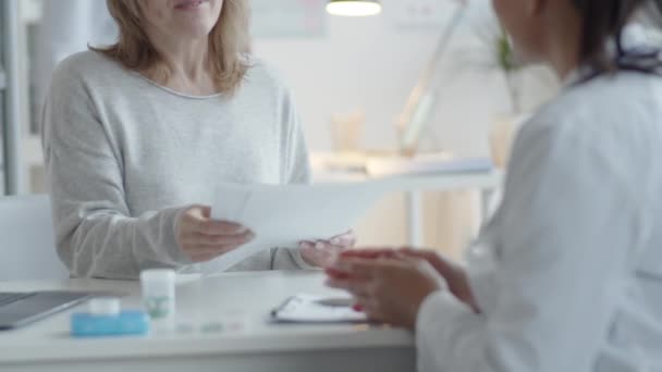 Yetişkin Sarışın Bir Kadının Kadın Doktorla Sıkışırken Klinikteki Masada Birlikte — Stok video