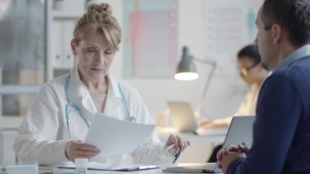 Média Idade Médico Vestindo Óculos Lendo História Médica Paciente Masculino — Vídeo de Stock