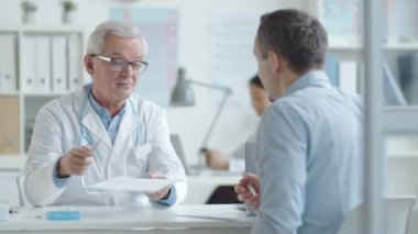 Erkek hasta, kliniği ziyaret ederken kıdemli doktoru el sıkışarak selamlıyor ve sağlık hizmeti anlaşması imzalıyor.