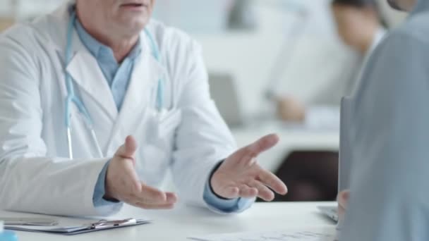 中段拍摄的成熟医生在临床会诊期间握手并向男性病人解释一些事情 — 图库视频影像