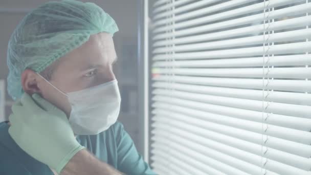 跟踪男性医务工作者戴着洗涤器和一次性帽子 摘下医疗面具 看着相机 微笑的胸部朝上拍下的照片 — 图库视频影像