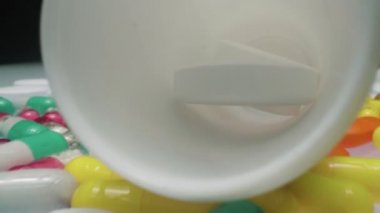 Çeşitli ilaç haplarını, kapsülleri, su toplayan tabletleri ve stüdyodaki plastik bardakları yakınlaştır.