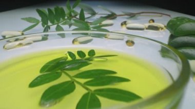 Klinik laboratuarındaki tek kullanımlık eldivenli bilim adamının elini yakınlaştır. Yeşil dallı, aloe vera yapraklı ve zeytinyağlı küçük bir kapsülün içine güzellik malzemeleri koy.