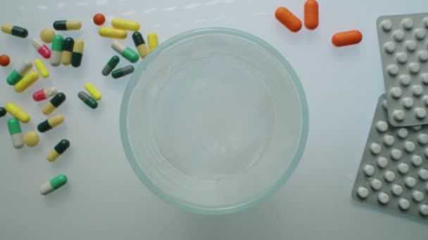 放大上视图拍摄的冒泡片掉落在杯水中 带着气泡和药丸的白色桌子上的气泡溶解了 — 图库视频影像
