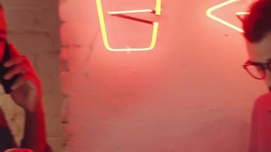 Orta Doğulu bir adam duvarda durup, neon ışıklarıyla süslenmiş ve akıllı telefondan daktilo çekerken genç Afrikalı Amerikalı bir adam telefonda sohbet ediyor ve modern çalışma alanında kahve içiyor.