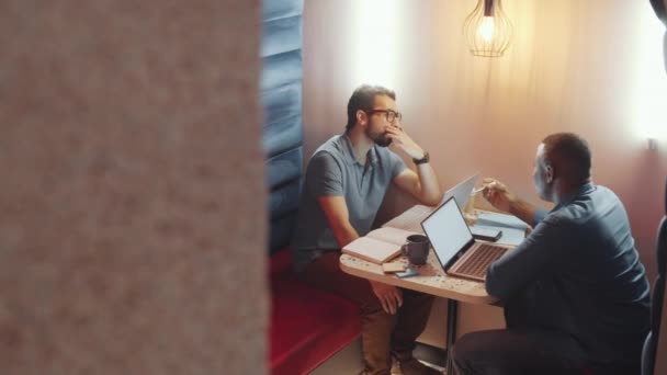 男性と話す若い中東の男の高い角度ビューアフリカ系アメリカ人の同僚コーヒーショップからリモートで作業しながら — ストック動画