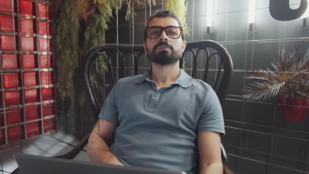 Młody Człowiek Środkowego Wschodu Okularach Siedzący Krześle Korzystający Laptopa Następnie — Wideo stockowe