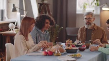 Kafkasyalı güzel anne, baba, genç kız ve oğlanın evde yemek yiyip sohbet ettikleri orta boy bir fotoğraf.