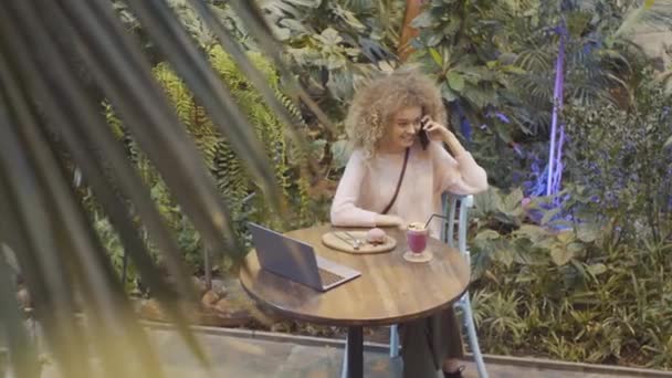 Sarışın Kıvırcık Saçlı Telefonda Sohbet Eden Smoothie Içen Genç Bir — Stok video