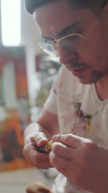 Erkek ressamın boya tüpünü kapatırken dikey çekimini kapat ve sonra boya renklerini palet bıçağıyla karıştır.