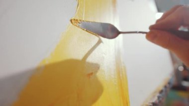 Ressamın el kamerasındaki resmini kapat. Çağdaş resim yaparken palet bıçağı kullanarak tuvale sarı boya yayıyor.