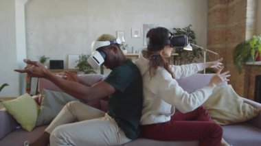 Evdeki koltukta sırt sırta oturan, video çalarken havada bir şeylere gülümseyen ve dokunan çok ırklı genç çift, VR kulaklıklarıyla birlikte geldi.