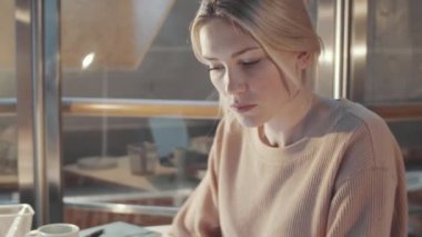 Sarışın kadın terzinin, gözlük takıp moda çizimleri izlerken stüdyoda yeni koleksiyon çalışmalarını çekeceğiz.