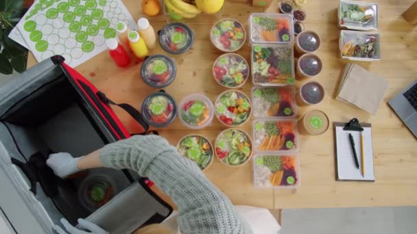 从上往下拍摄的女工人手套 她们把装有健康食品和有机饮料的生态容器装进了食物运送袋 — 图库视频影像