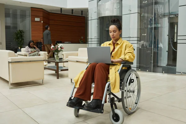 Pessoa em uma cadeira de rodas usando um laptop — Fotografia de Stock