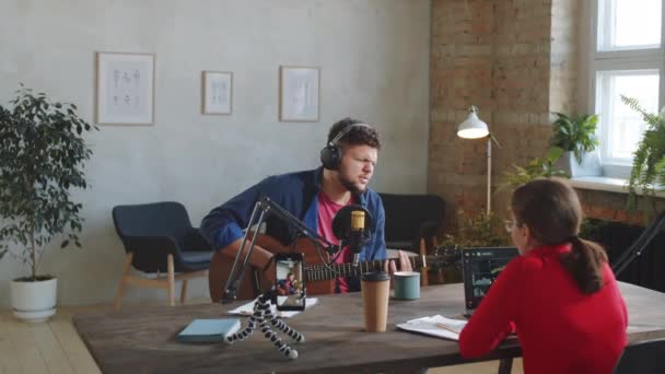 Young Man Headphones Playing Guitar Singing Microphone While Sitting Studio — Stock Video