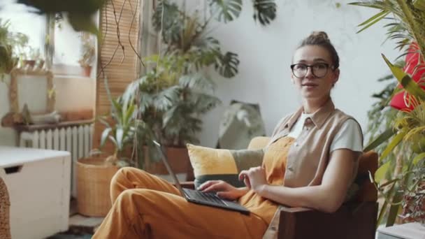 Neşeli Beyaz Kadın Kucağında Dizüstü Bilgisayarla Koltukta Oturuyor Gülümseyen Kameraya — Stok video
