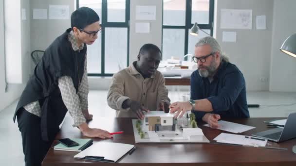 オフィステーブルで建築模型を議論しながらチームでプロジェクトに取り組む多様な男性 女性の多才建築家のグループ — ストック動画