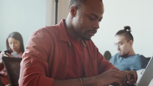 Närbild Ung Koncentrerad Man Afroamerikansk Etnicitet Arbetar Laptop Vid Skrivbordet — Stockvideo