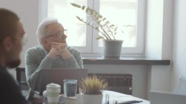 Beyaz tahtaya iş grafiği çizen ve ofis toplantısı sırasında melez çalışanlardan oluşan bir ekibe sunum yapan çekici melez bir kadın patron.