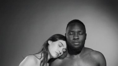 Siyah beyaz bir portre. Beyaz güzel beyaz bir kadın. Afro-Amerikalı erkek arkadaşının omzuna yaslanmış.