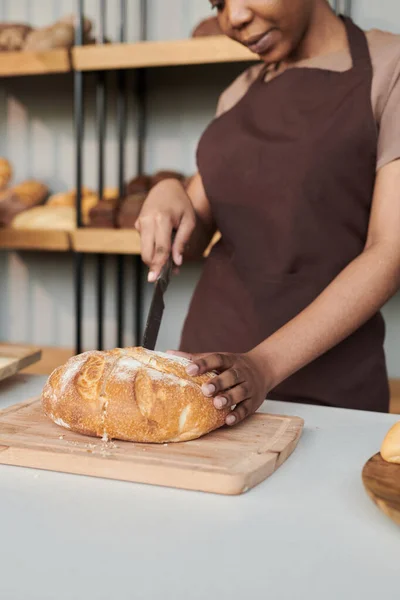 Ung kvinna skär färskt bröd — Stockfoto