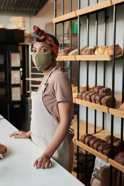 Пекарь в маске работает в пекарне — стоковое фото