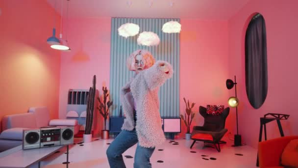 年轻的金发女舞蹈演员穿着华丽的服装 在时尚工作室里跳舞 带着老式内饰和粉色霓虹灯的相机 — 图库视频影像