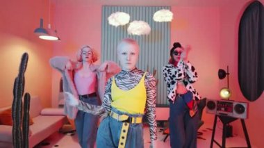 Hippi kıyafetli, etkileyici genç bayan dansçıların görüntüsünü büyüt. El hareketleri yapıp kameraya yaklaşırken son moda stüdyoda pembe ışıkla dans eden kadın vogue.