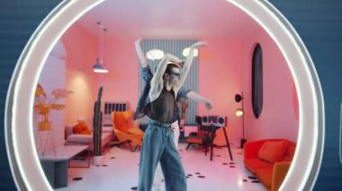 Moda kıyafetleri içinde iki arsız gencin birlikte egzantrik vogue dansı yaptığı ve retro stüdyosunda yuvarlak ışıklı kapı aralığında kamera önünde poz verdiği görüntüleri yakınlaştırın.