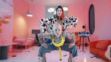 Moda kıyafetleri içindeki iki etkileyici kadının, retro stüdyosunda, aydınlatılmış yuvarlak kapı aralığıyla birlikte dramatik vogue dansı yaparken görüntüsünü büyüt.
