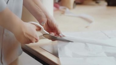 Çiçekçide masa başında çalışırken tanınmayan kadın çiçekçinin el makası ile kağıt keserken yakın plan çekimleri.