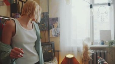 Genç, rahat kadın sigara içiyor ve rahat retro odasında dans ediyor. Erkek arkadaşı ise yatakta içki içip konuşuyor.