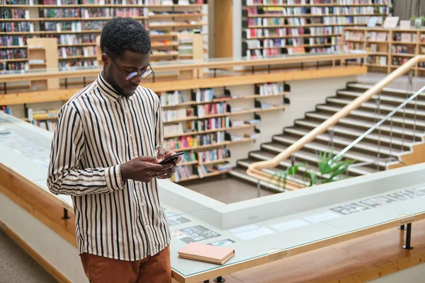 Mann benutzt Telefon in der Bibliothek — Stockfoto