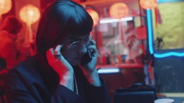Cinsiyet değiştiren adam barda oturuyor, cep telefonuyla konuşuyor, sonra üzülüyor, peruğunu ve gözlüklerini çıkarıyor ve ağlıyor.