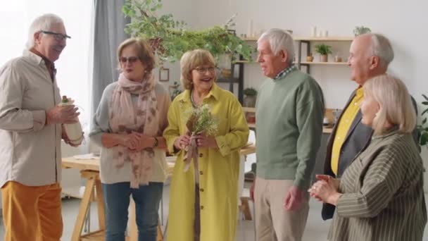 Kompania Starszych Przyjaciół Stojących Razem Domu Kwiatami Winem Uśmiechających Się — Wideo stockowe