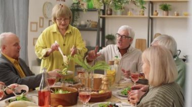 Evde akşam yemeği partisi verirken, son sınıf öğrencisinin arkadaşları için tabağa salata koyarkenki görüntüsü.