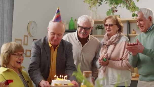 Glückliche Seniorin Sitzt Esstisch Bläst Kerzen Auf Geburtstagstorte Und Lächelt — Stockvideo