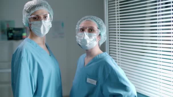 Dos Enfermeras Jóvenes Con Máscaras Protectoras Anteojos Sombreros Estériles Uniformes — Vídeos de Stock