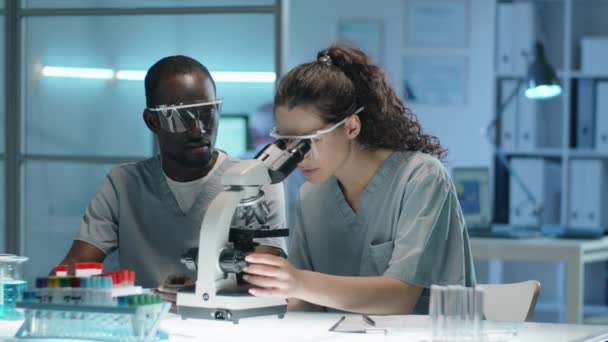 Young Caucasian Female Scientist Using Microscope Afro American Male Colleague — Stock Video