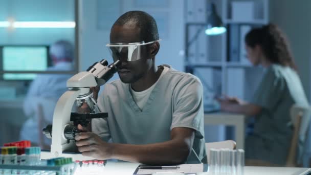 Νεαρός Αφρο Αμερικανός Επιστήμονας Στολή Και Προστατευτικά Γυαλιά Κοιτάζοντας Μέσα — Αρχείο Βίντεο